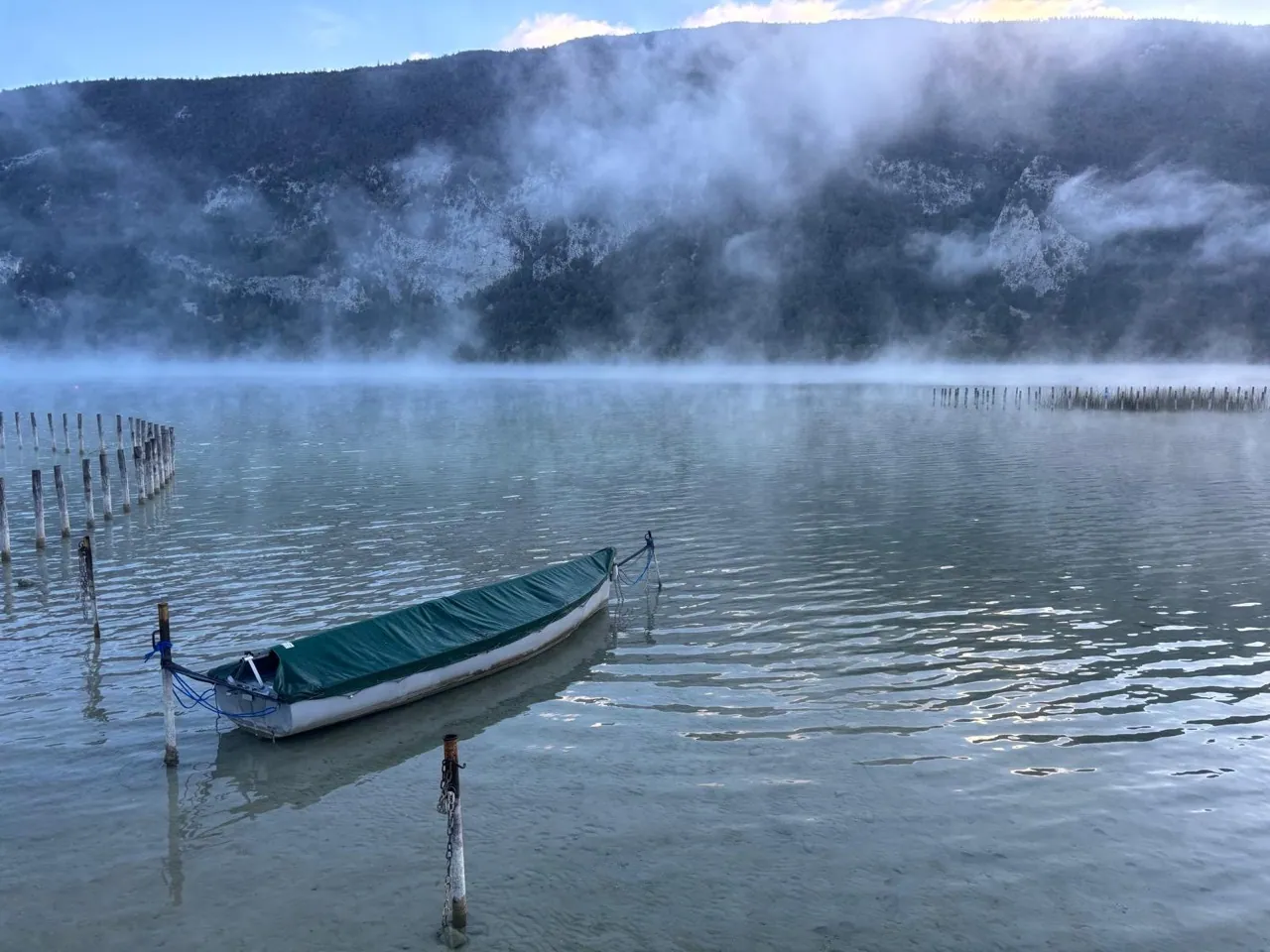 Une barque sur le lac d’Aiguebelette, au pied des montagnes dans la brume